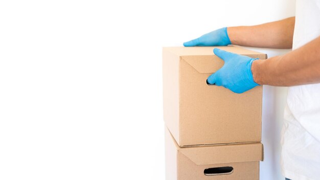 Delivery man holding cardboard boxes in blue rubber gloves with copy space fast and free delivery tr...