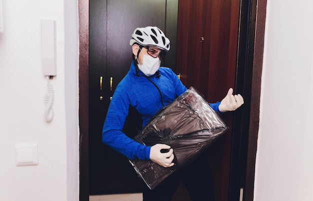 写真 医療用ゴム手袋とマスクで紙箱を握る配達員 コピースペース 迅速で無料の配達輸送 オンラインショッピングとエクスプレス配達 隔離
