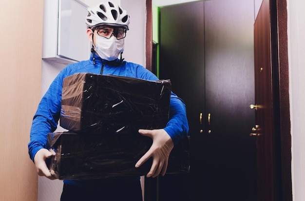 Photo delivery man holding cardboard boxes in medical rubber gloves and mask copy space fast and free delivery transport online shopping and express delivery quarantine