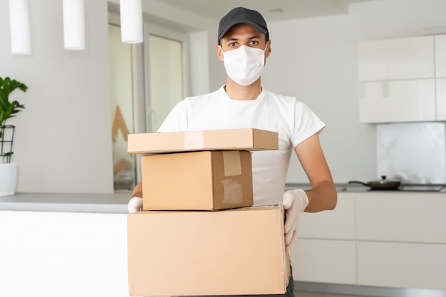 Delivery man holding cardboard boxes in medical rubber gloves and mask. copy space. Fast and free Delivery transport . Online shopping and Express delivery . Quarantine