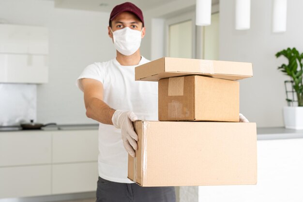 Delivery man holding cardboard boxes in medical rubber gloves and mask. copy space. Fast and free Delivery transport . Online shopping and Express delivery . Quarantine