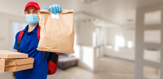 Delivery man holding cardboard packages in medical rubber gloves and mask. copy space. Fast and free Delivery. Online shopping and Express delivery . Quarantine.