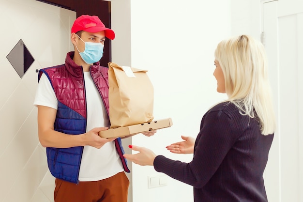 Foto fattorino che tiene in mano un sacchetto di carta con cibo su sfondo bianco, fattorino in maschera protettiva