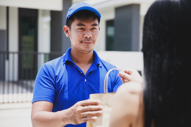 写真 食品パッケージを保持している青いtシャツの配達人