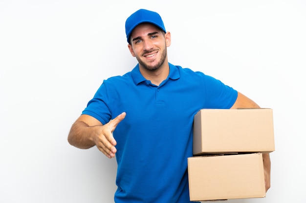 Delivery man over isolated white  handshaking after good deal