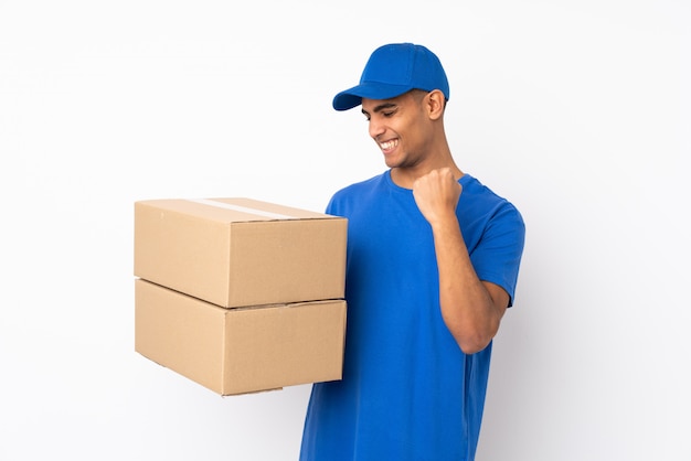 Delivery man over isolated white wall celebrating a victory