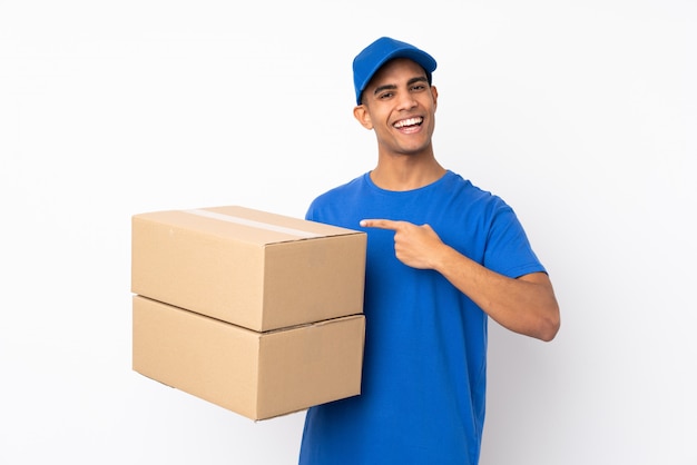 Delivery man over isolated white wall and pointing it