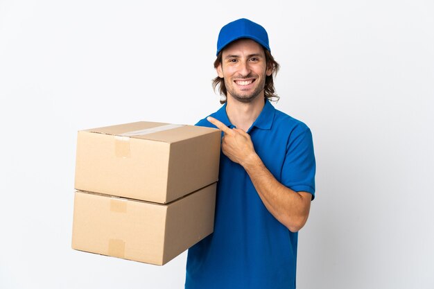 Delivery man isolated on white wall pointing to the side to present a product