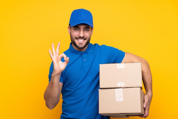 Delivery man over isolated yellow wall