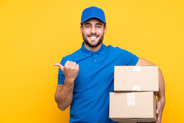 Delivery man over isolated yellow wall