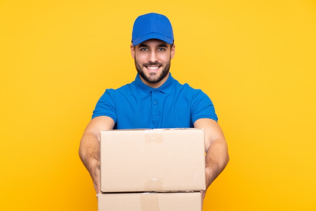 Delivery man over isolated yellow with happy expression