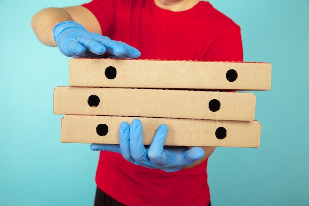 Foto fattorino in vestiti rossi con tre scatole di pizza.