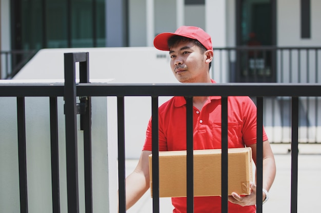 Delivery man in a red t-shirt holding cardboard box