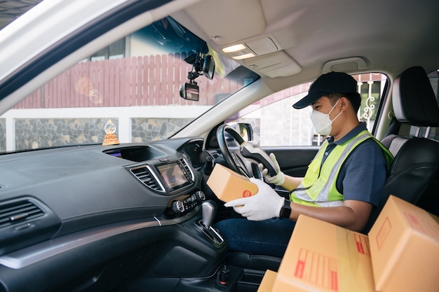 A delivery man using a credit card reader. In the van with parcels on the outside of the warehouse. Delivery