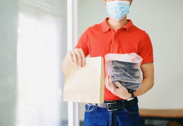 Delivery man wearing face mask and hand holding food packaging Service food delivery to home