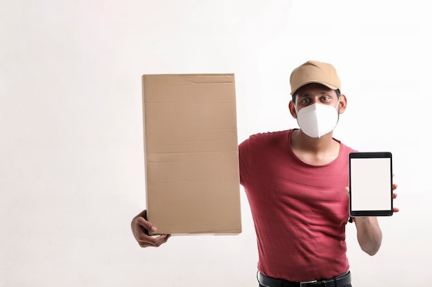 Delivery Man Wearing Medical Mask and Showing Smartphone screen with Box in Hands. Home Delivery. Order Online Technology.