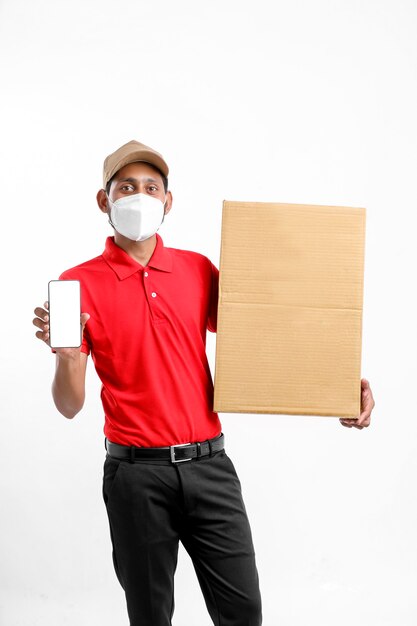 Delivery Man Wearing Medical Mask and Showing Smartphone screen with Box in Hands. Home Delivery. Order Online Technology.