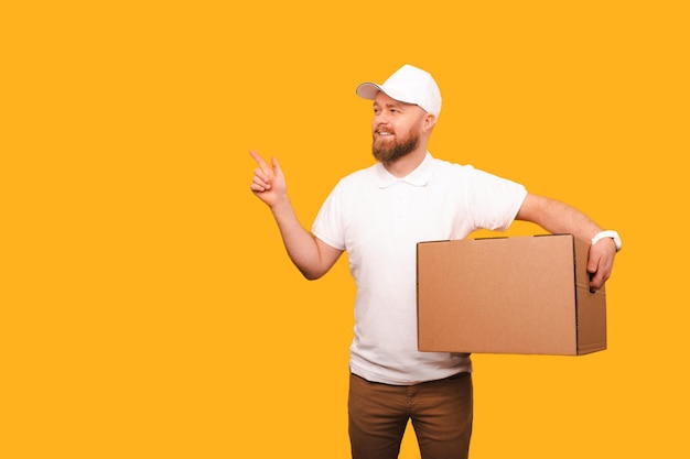 Delivery man in white holds a box and points aside at the yellow copy space