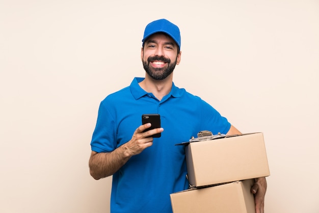 Delivery man with beard over isolated sending a message with the mobile