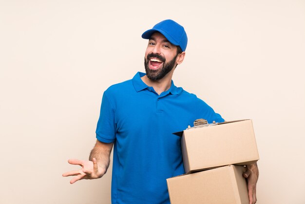 Delivery man with beard over isolated wall smiling