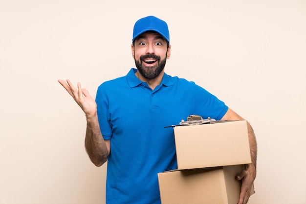 Delivery man with beard over isolated wall with shocked facial expression