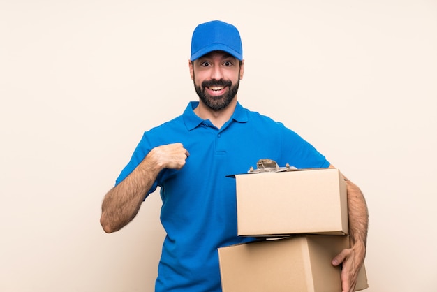 Delivery man with beard over isolated wall with surprise facial expression