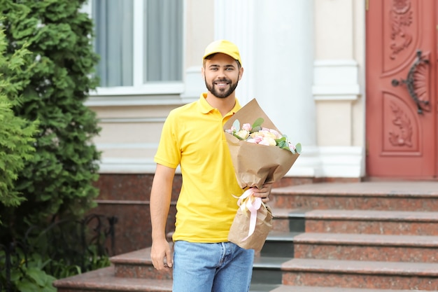 Photo delivery man with bouquet of beautiful flowers outdoors