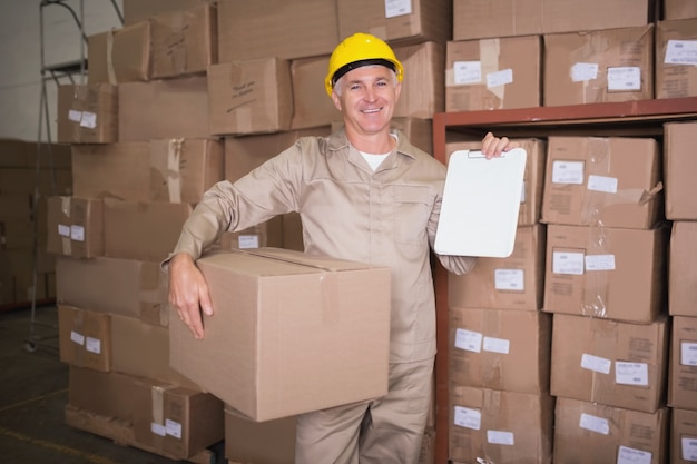 Delivery man with box and clipboard in warehouse