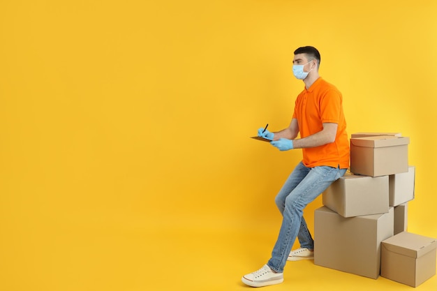 Delivery man with clipboard on yellow background with boxes