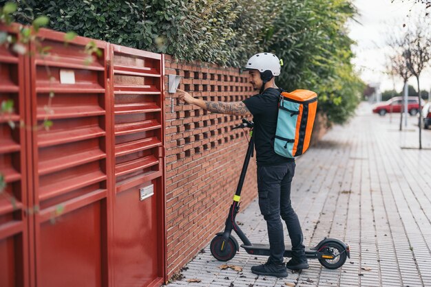 Delivery man with electric skateboard ringing the doorbell