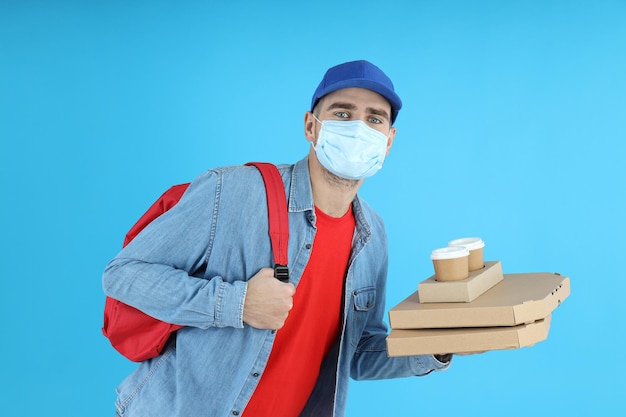 Delivery man with food on blue background