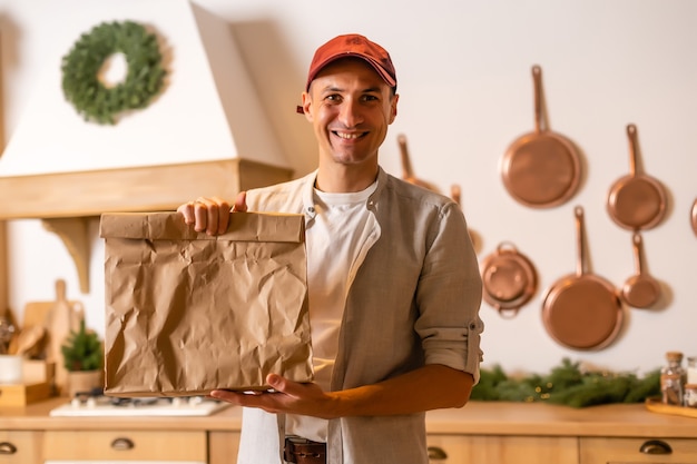 a delivery man with a package of food stands in a Christmas interior