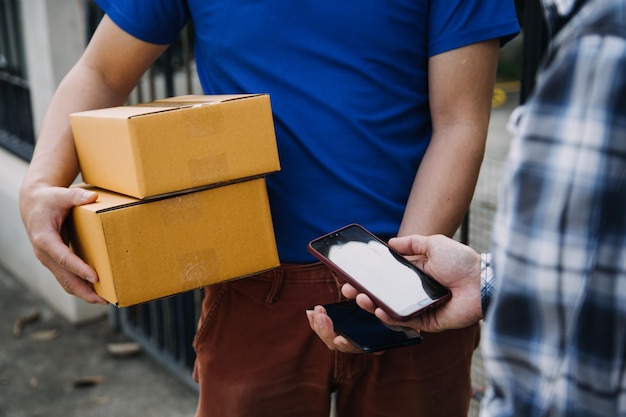 Photo delivery man with protective mask and gloves delivering parcels during lockdown and pandemic and holding mobile contactless payment machine