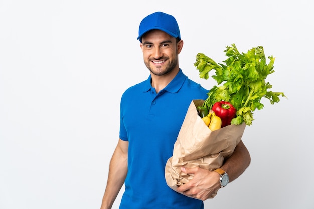 Delivery man with vegetables isolated  with happy expression