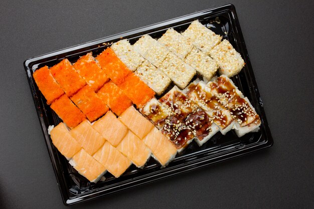 Доставка японской еды на дом. набор роллов с угрем, семгой, сыром, икрой летучей рыбы, кунжутом