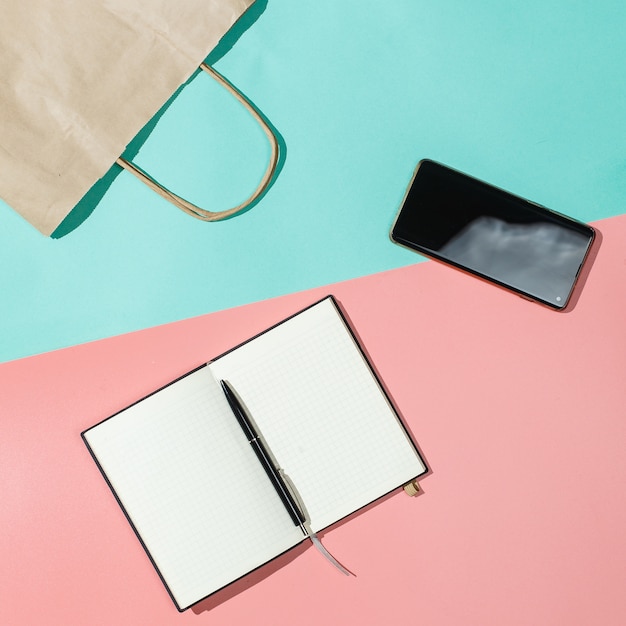 Delivery package, phone and notebook on a pink turquose