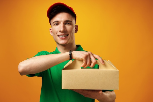 Delivery person holding parcel with food delivery against\
yellow background