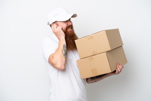 Delivery reddish man isolated on white background frustrated and covering ears