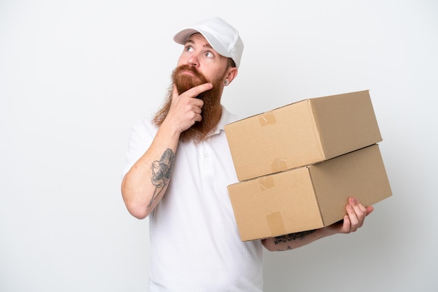 Delivery reddish man isolated on white background having doubts