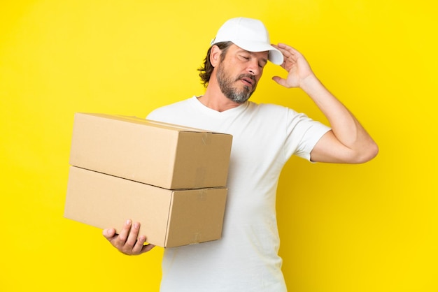 Delivery senior dutch man isolated on yellow background with headache