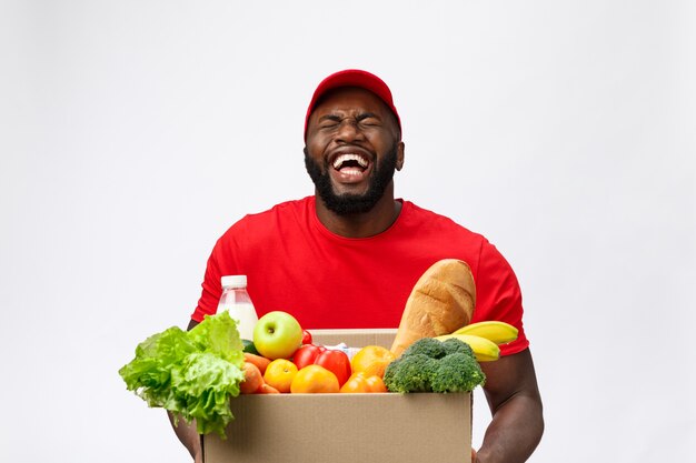 Delivery service - Handsome African American delivery man carrying package box of grocery food and drink from store.  