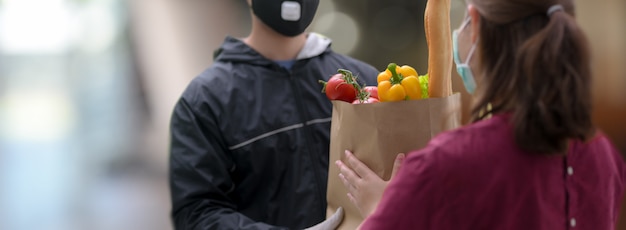 Foto uomo di servizio di consegna che consegna la borsa dell'alimento fresco al cliente femminile