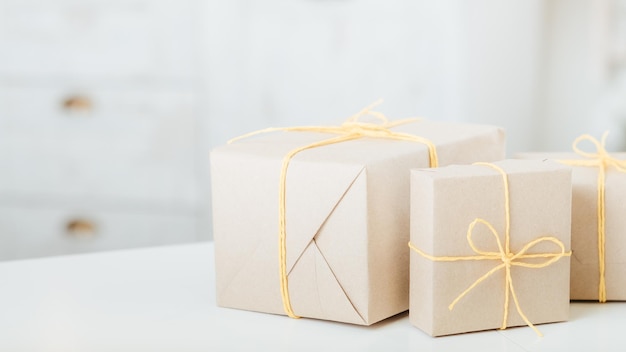 Delivery service Rustic paper handmade gift boxes on white table over defocused white background Copy space