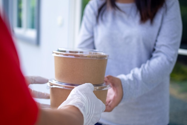 Delivery staff wear gloves for good hygiene, send food boxes to recipients in front of the house. Order food online and fast delivery.