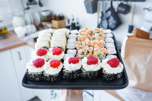 delivery of sushi and rolls set is hold in hand in the interior modern kitchen of house
