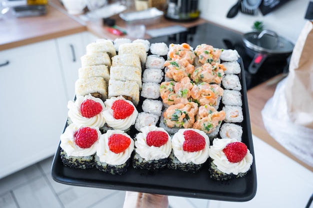 delivery of sushi and rolls set is hold in hand in the interior modern kitchen of house