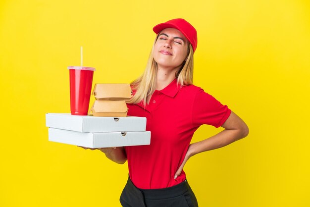 Consegna donna uruguaiana che tiene un fast food isolato su sfondo giallo che soffre di mal di schiena per aver fatto uno sforzo