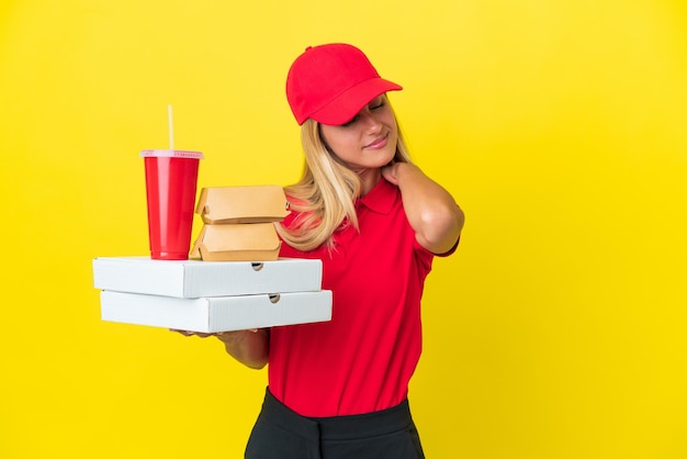 Foto consegna donna uruguaiana in possesso di fast food isolato su sfondo giallo che soffre di dolore alla spalla per aver fatto uno sforzo