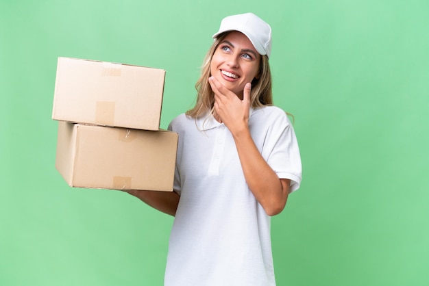 Delivery Uruguayan woman over isolated background looking up while smiling