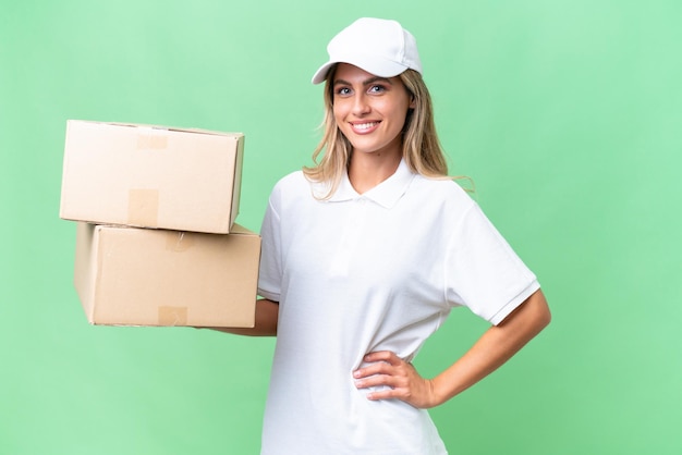 Delivery Uruguayan woman over isolated background posing with arms at hip and smiling